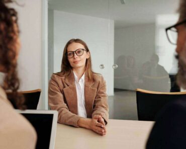 Femme en entretien d'embauche, échangeant avec deux recruteurs.