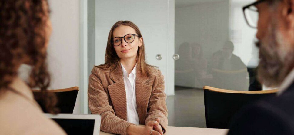 Femme en entretien d'embauche, échangeant avec deux recruteurs.